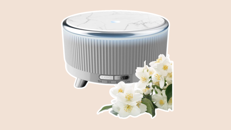 An oil diffuser with white flowers next to it.