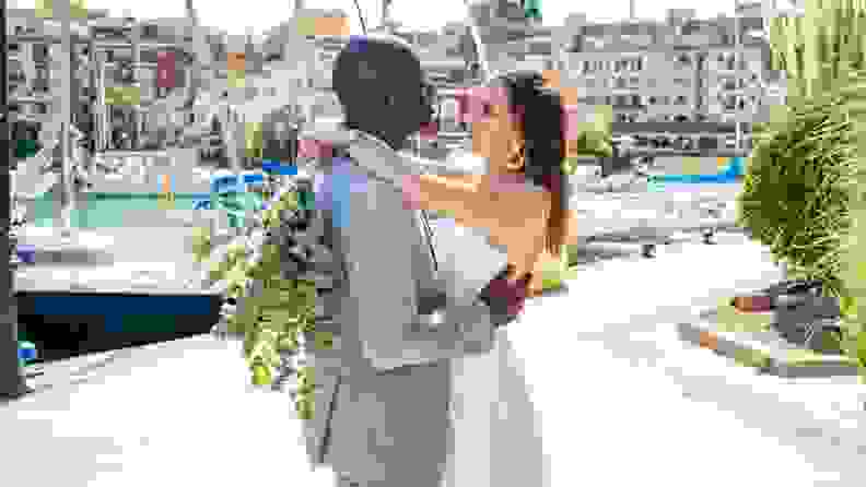 A newly married couple embraces in a harbor on the coast of Spain