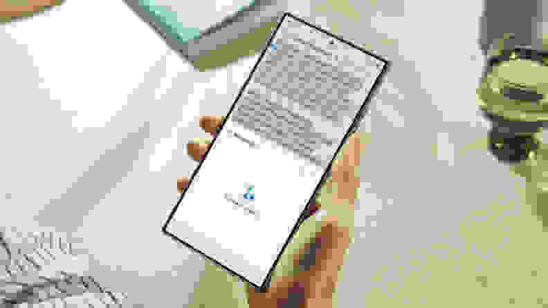 A person holds the Samsung S24 Ultra in their right hand. It is being used to transcribe audio.