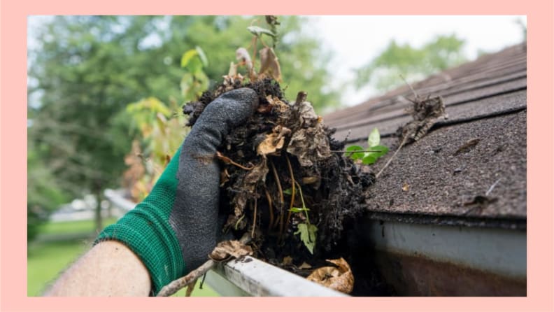 Hands with work gloves cleaning leaves from gutter