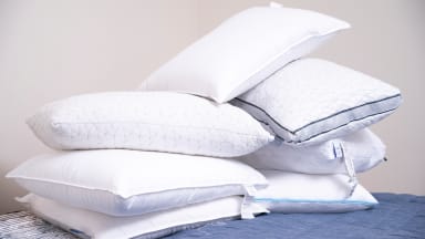 a pile of pillows including the casper, coop, brooklinen and amazon basics on a bed
