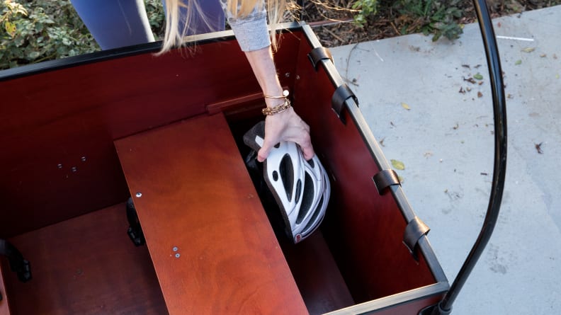 A person puts a bike helmet into the storage compartment of the Bunch Bike