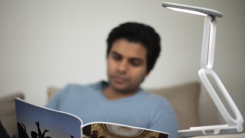 A person reads a book with the Lili Lamp overhead.