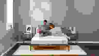 A couple sitting on a Tuft and Needle mattress.