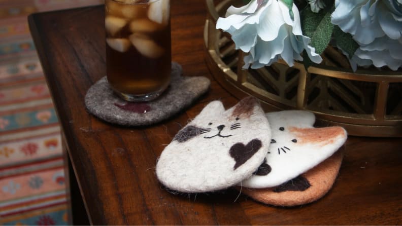 An image of three cat coasters stacked together on a tabletop.
