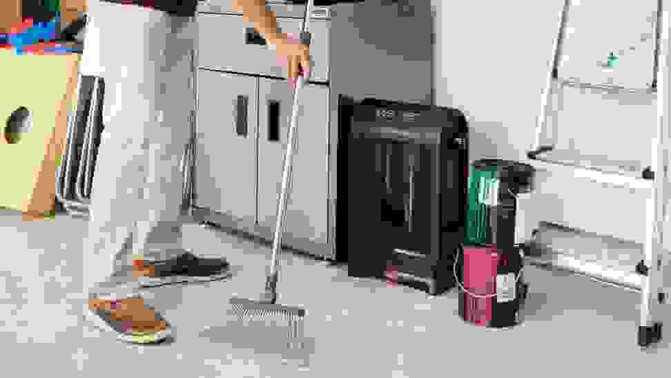 A man using his electric dustpan to clean his garage.