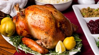 Cooked turkey on a plate with fruit and herbs.