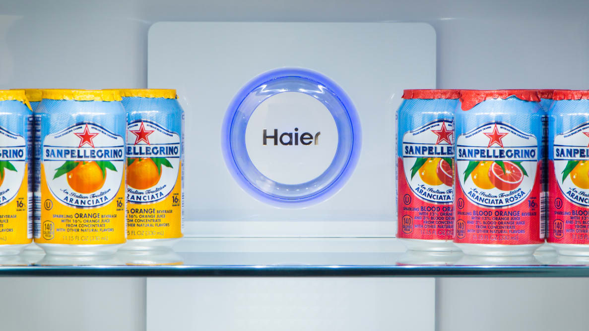 A fridge shelf is stocked with colorful cans of soda