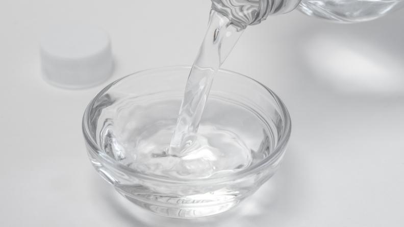 Pouring white distilled vinegar in a bowl.