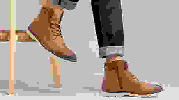 A person modeling a pair of tan motorcycle boots.