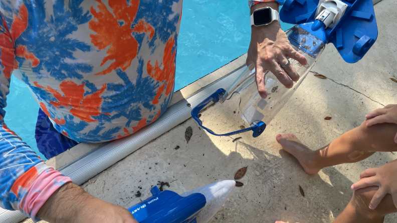 Person dumping out filter chamber inside of the Sharper Image Rechargeable Pool Vacuum.