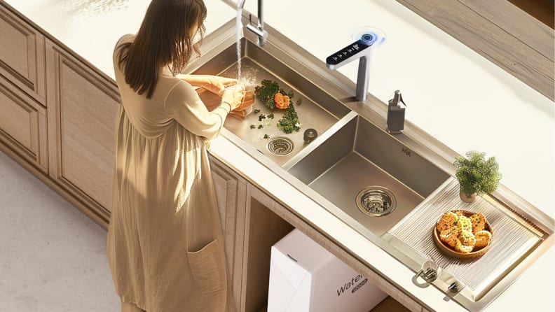 A woman stands at a sink washing produce