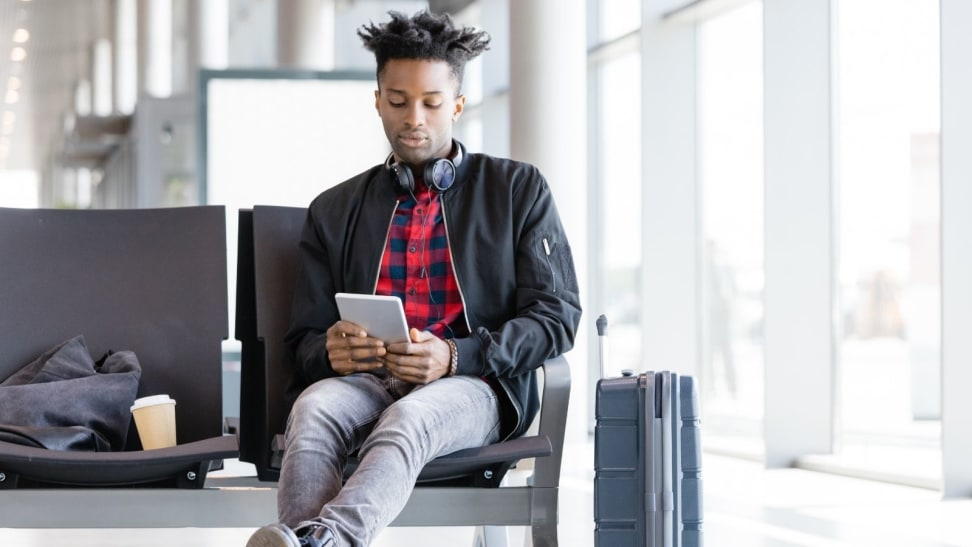 Man wearing a leather flight jacket while looking at tablet.