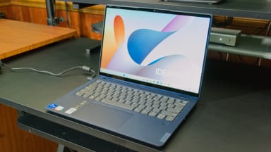 Blue Lenovo IdeaPad Flex 5i 14 Laptop with display turned on while on top of black desk surface.
