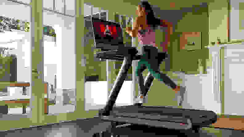 woman in green leggings running on peloton tread