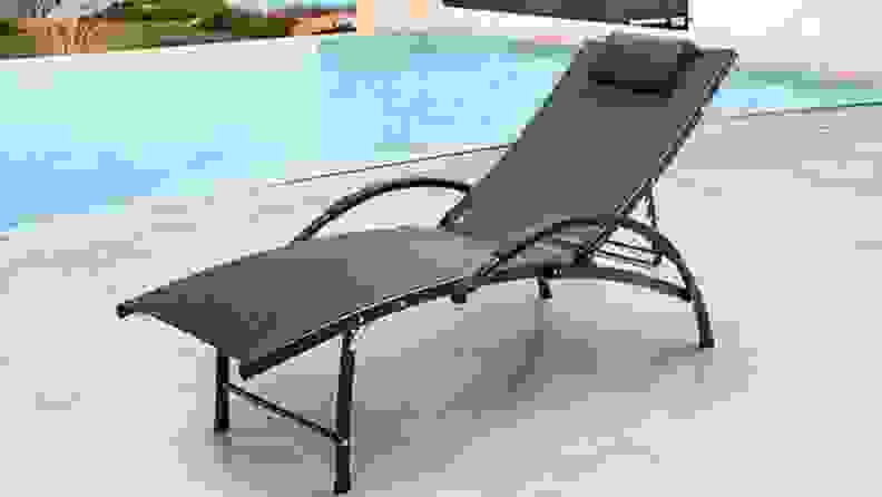 A deck chair besides a swimming pool.