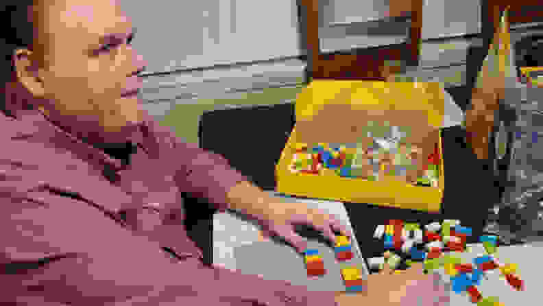 A man putting the Lego Braille Bricks together.