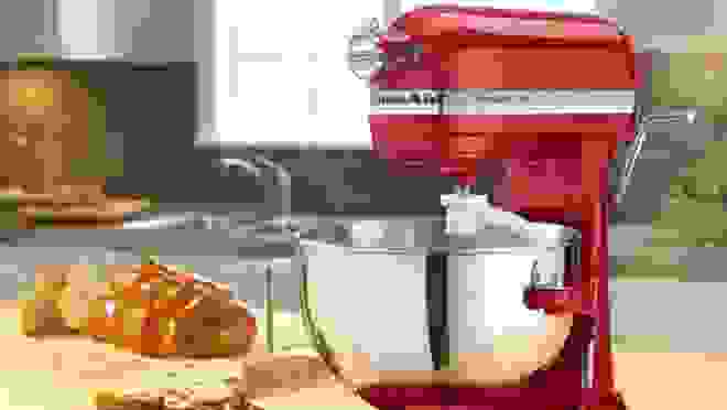 Red standing mixer on countertop next to bread loaf