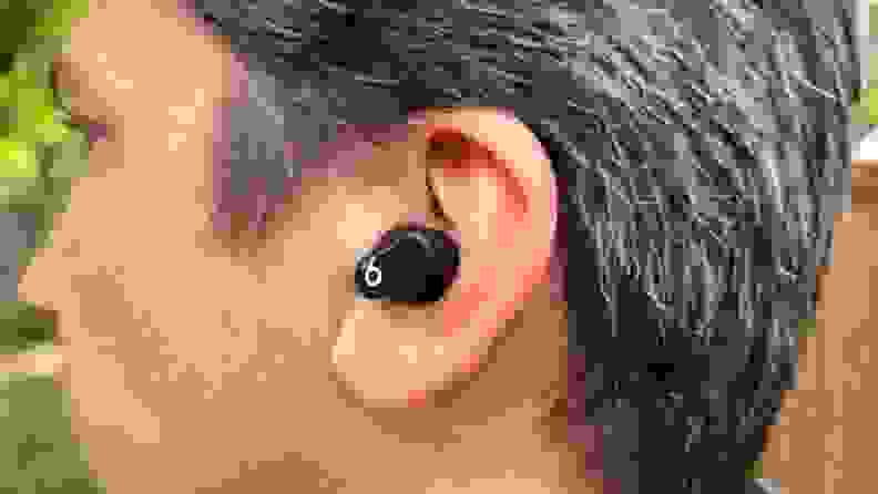 A man with brown and grey hair is shown from the back with the black Beats Studio Bud in his left ear.