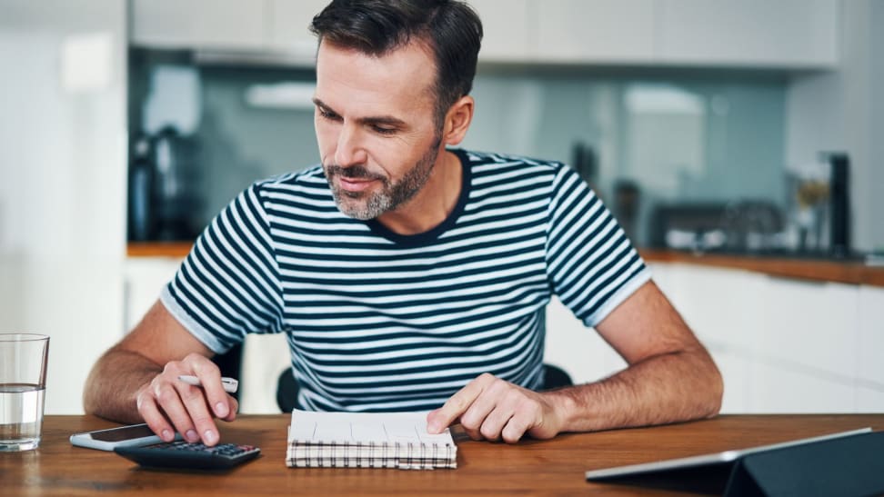 Man creating 50/30/20 budget with calculator