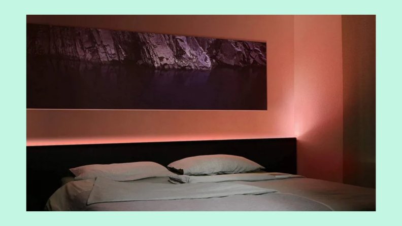 A light strip illuminates a bedroom in a shade of peach