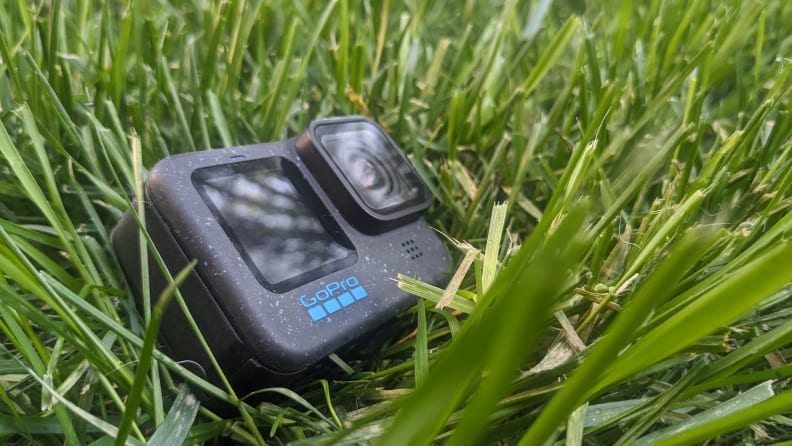 The GoPro Hero12 Black on the ground surrounded by grass in an outdoor setting.