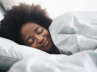 Woman sleeping happily in bed with white covers