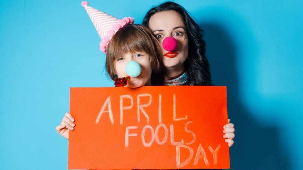 Happy mother with her daughter holding a red sheet of paper with the inscription April Fools' Day.