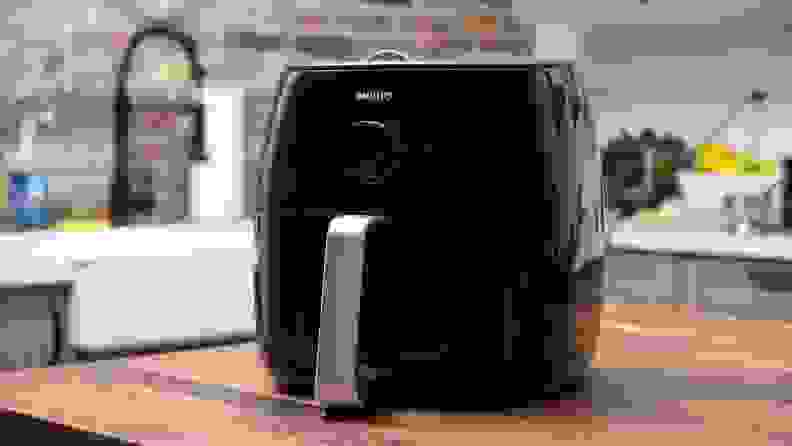 A black Philips air fryer is displayed on a kitchen island.