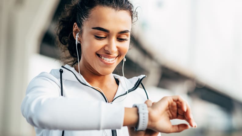 A woman looking at a fitness tracker on her wrist.
