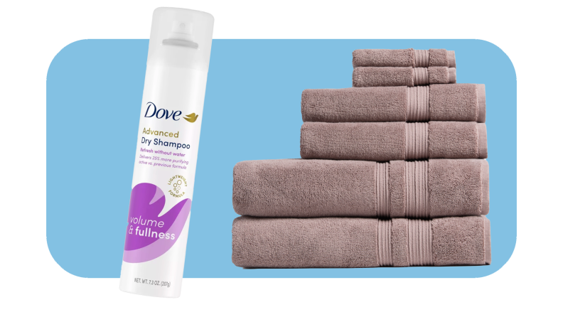 Purple and white can of dry shampoo next to plum colored stack of towels.