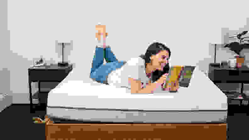 a person lies on their stomach reading on the purple mattress