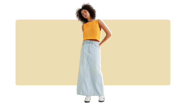A model wearing an oversized light blue denim maxi skirt with a yellow top.