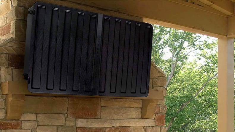 A closed Storm Shell outdoor TV enclosure mounted to stone work on an outdoor patio.