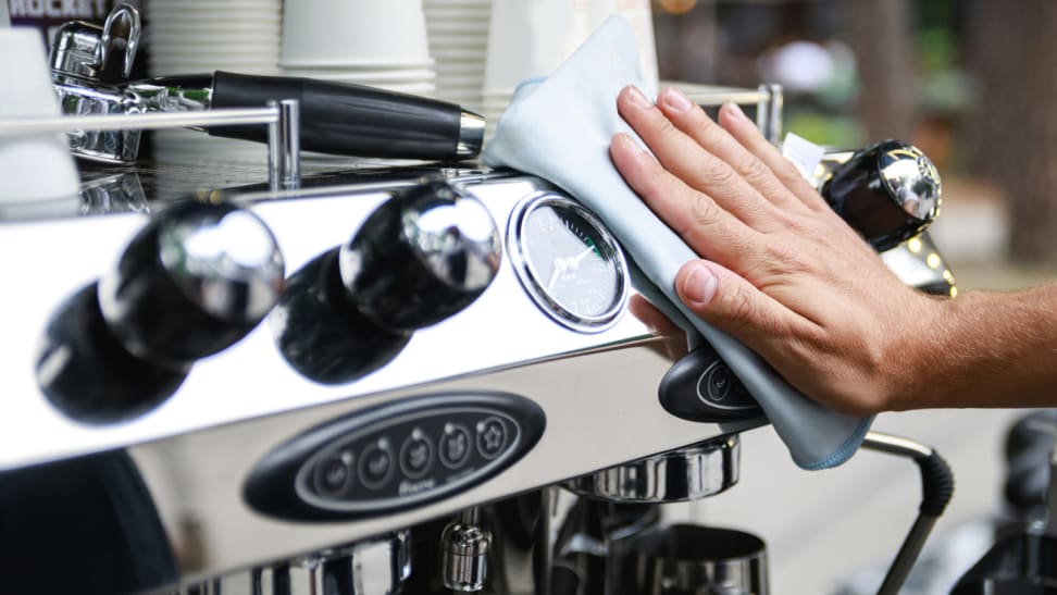 A barista wipes an espresso machine after a day of work.