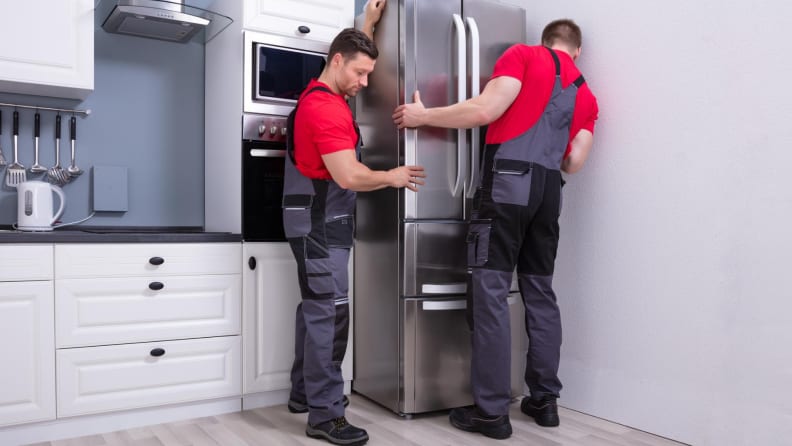 two men setting up a refrigerator