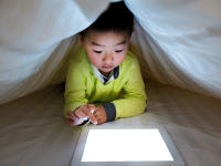 Kid on tablet under the covers