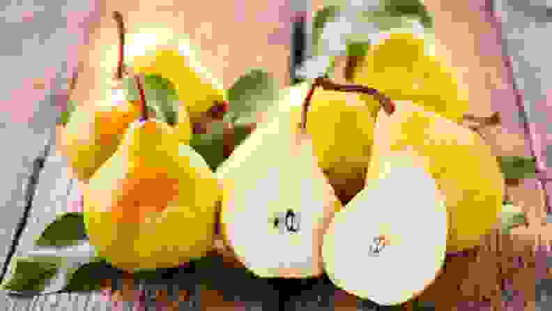 An image of 6 golden pears, one of which is sliced in half.