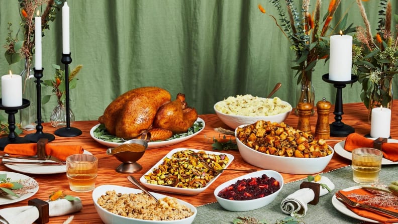 A Thanksgiving feast on an elaborately decorated table with sliced holiday turkey and various side dishes.