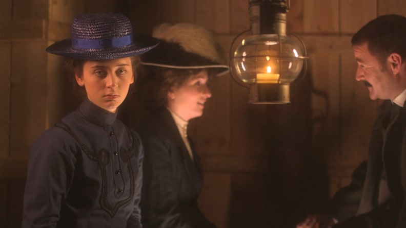 Three people in period clothing talk