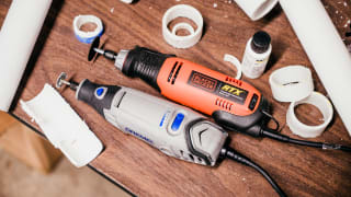 Black and decker rotary tool and a dremel sit side by side on a work bench surrounded by cut pipes