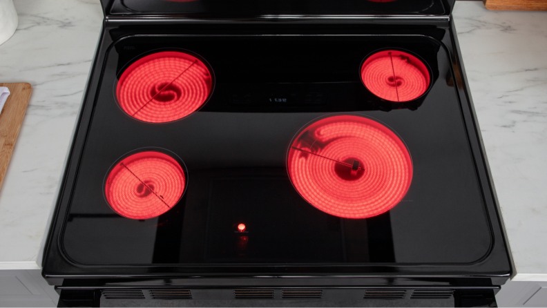 The stovetop of the electric range with all four burners turned on and glowing red.