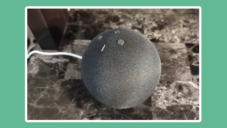 Gray 5th generation Amazon Echo Dot virtual assistant speaker on granite surface.