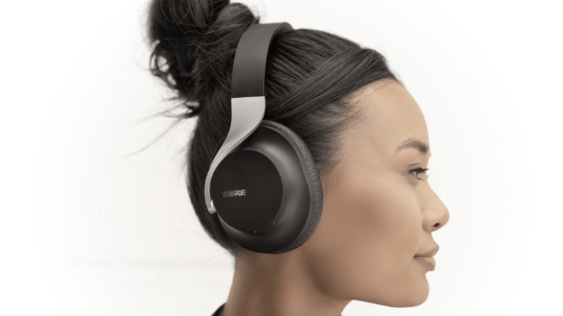 A pair of stylish black headphones with a silver band and ergonomic curves sit on a woman's head