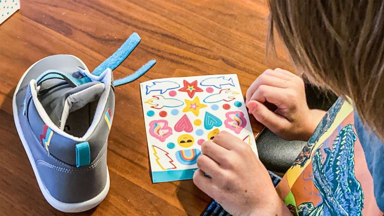 A child decorates their shoes with fun stickers.