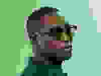Black man wearing green tinted sunglasses on green background