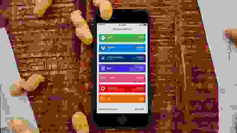 一张木床上放着一部iPhone，上面散落着花生，中间的一部iPhone显示着鲍比的主屏幕上的订阅列表。