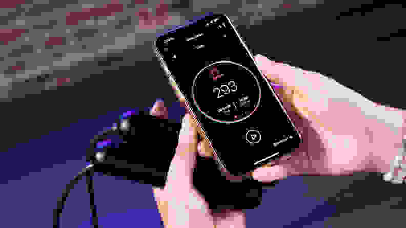 Person holding smart phone in one hand to operate the SmartRope app and SmartRope in the other.