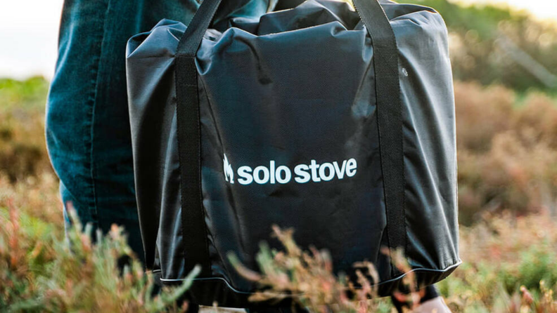 A person carries a Solo Stove in a case.