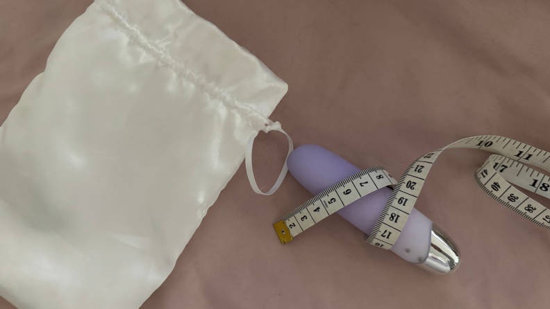Vibrator on a pink sheet with measuring tape